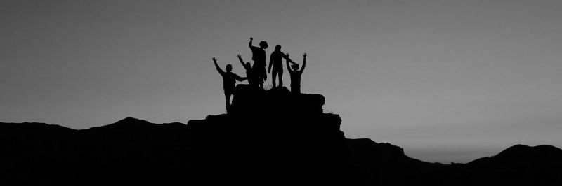 Group of people in silouette, waving on hill top in distance