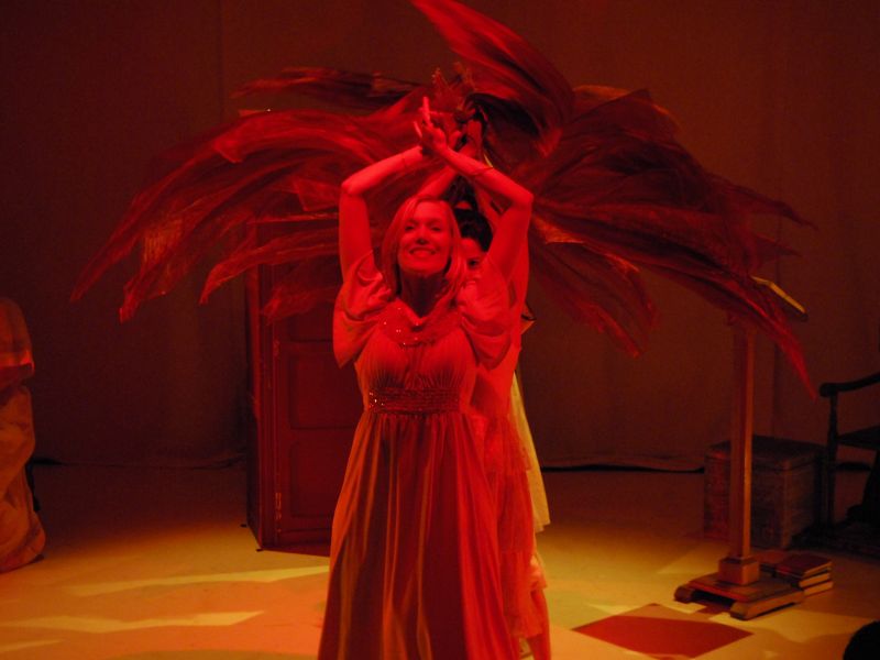 Anitra and a harem of girls are performing a dance with their veils barefoot. They are lined with fronted by Anitra. The wavering veils are replacing everybody&#039;s arms. The lighting is a mix of amber and red.