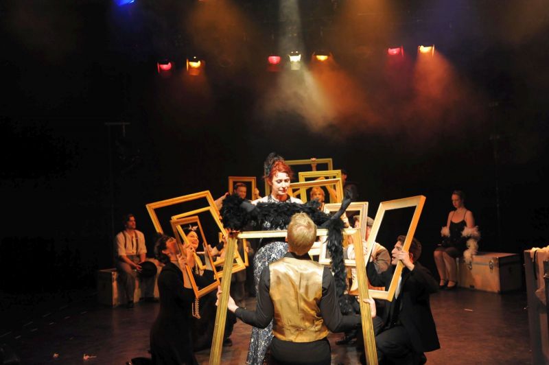 Kabaret Button-Moulder performs in a speakeasy. She is surrounded by the full company of piucture frames, who complement her performance.