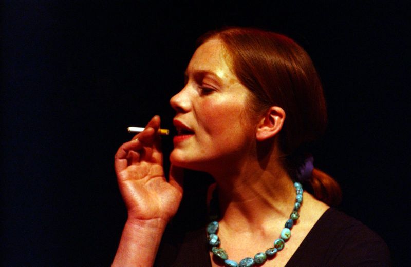 Head shot of a woman (Madam) with a necklace and a cigarette.